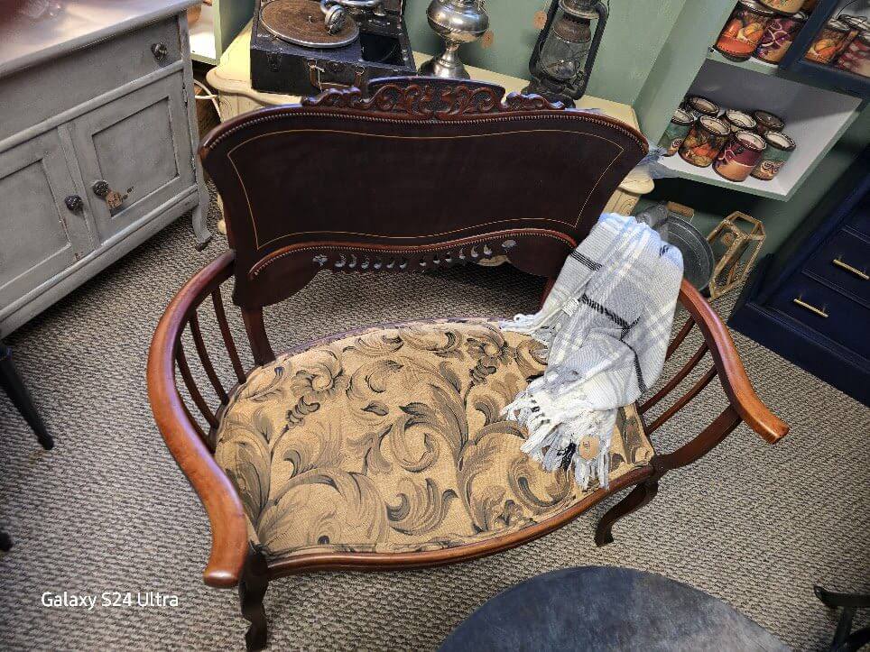 Antique wooden chair with floral cushion and wrapped fabric on seat.
