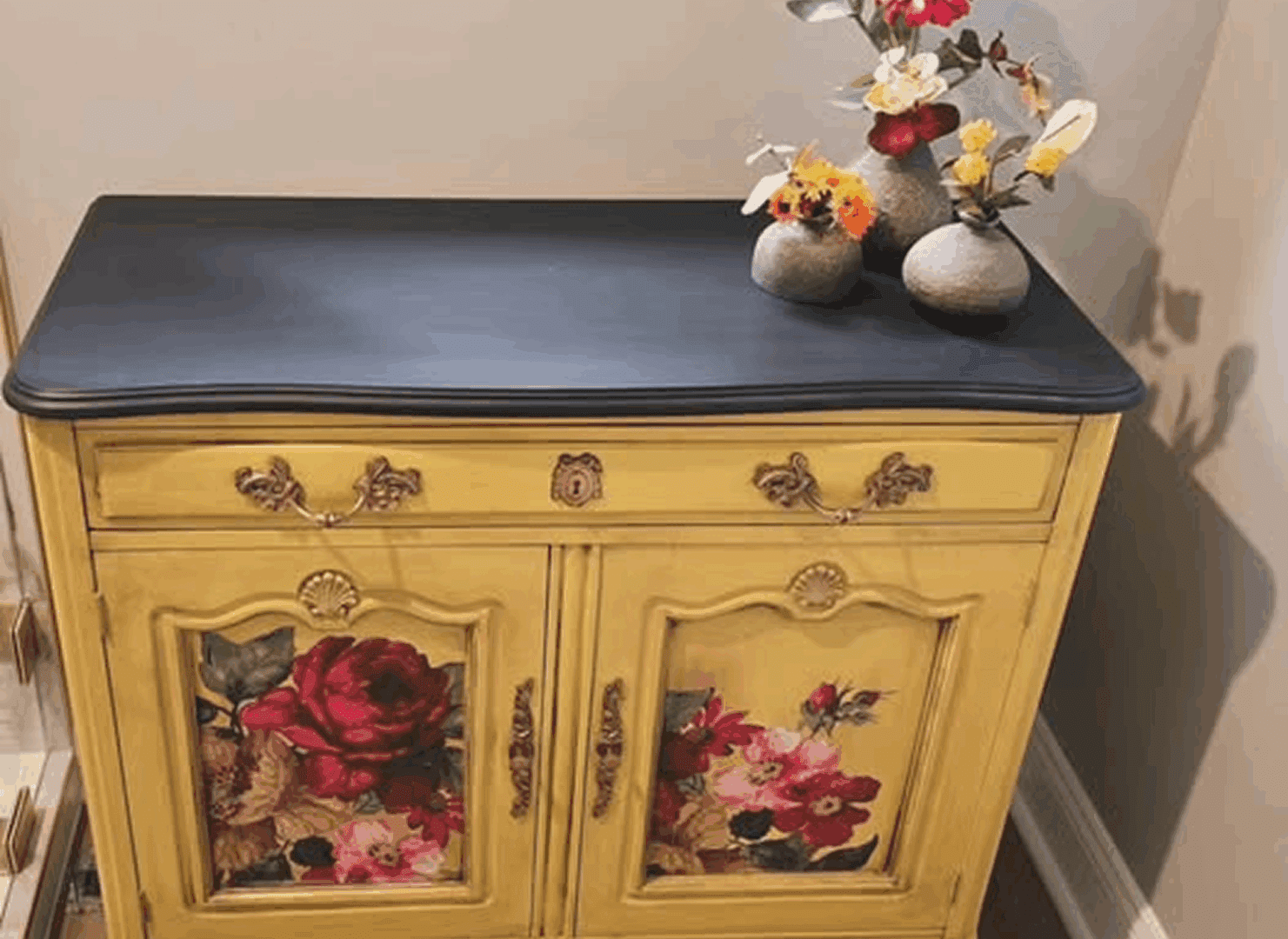 Vintage yellow cabinet with floral designs and dark top.