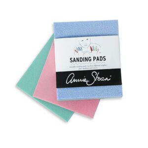 Three colorful sanding pads in blue, pink, and green.