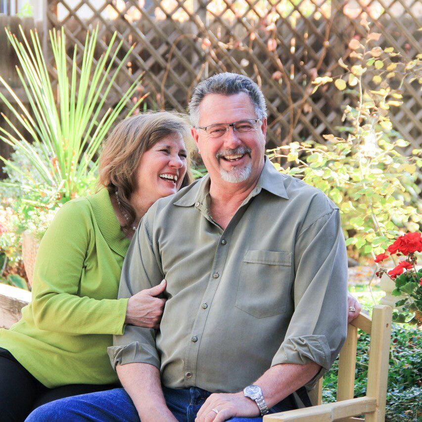 Happy couple enjoying a sunny day outdoors surrounded by greenery.